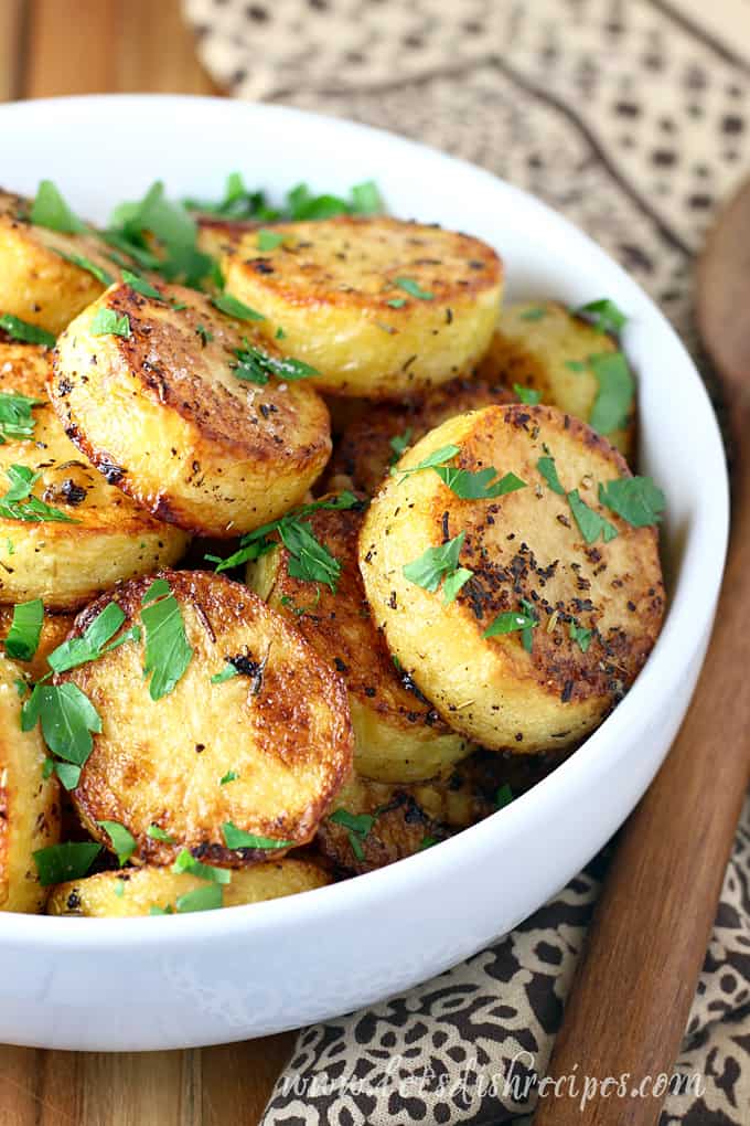 Roasted melting potato slices in white bowl.